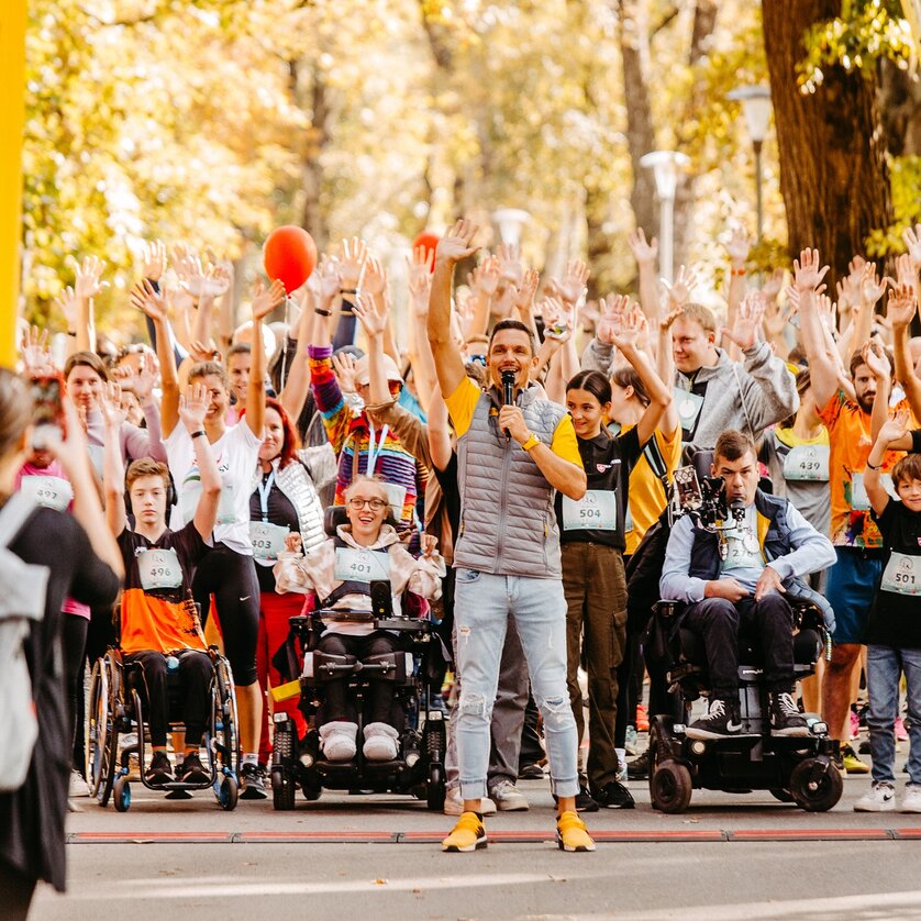 Teilnehmer in Rollstühlen heben die Hände zur Begrüßung beim Grazer Inklusionslauf. | © Mario Sudy