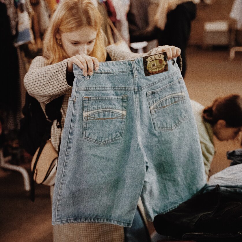 Una donna osserva dei jeans in una vendita vintage. | © BeThrifty