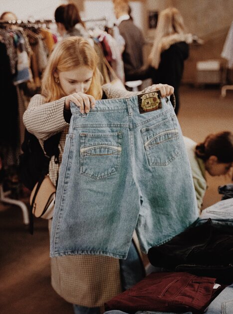 Una donna osserva dei jeans in una vendita vintage. | © BeThrifty