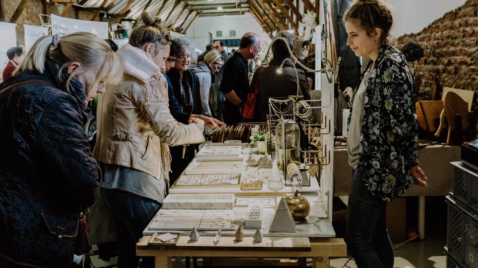 Interazione tra persone in un mercato dell'arte e del design a Graz. | © Kunst- und Designmarkt