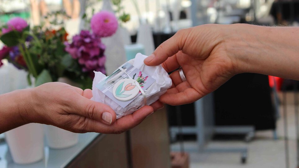 Una mano sta consegnando un regalo avvolto al mercato della ceramica.
