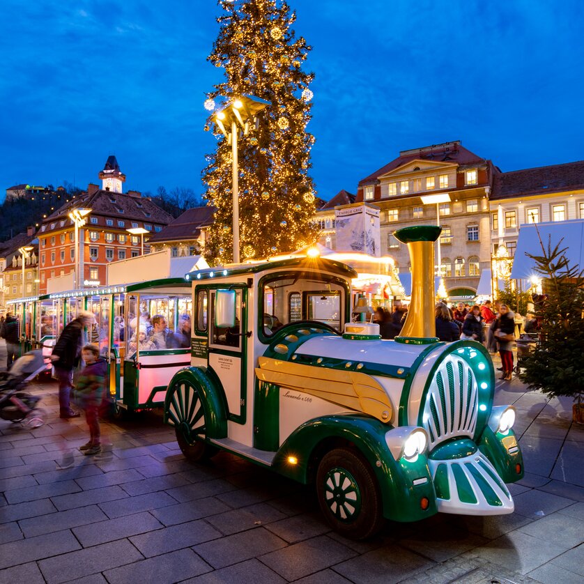 Advent in Graz I Adventzug | © Graz Tourismus-Harry Schiffer Eine festliche Stadtansicht von Graz zur Adventszeit mit einem beleuchteten Adventzug, der durch die Straßen fährt. | © Graz Tourismus-Harry Schiffer
