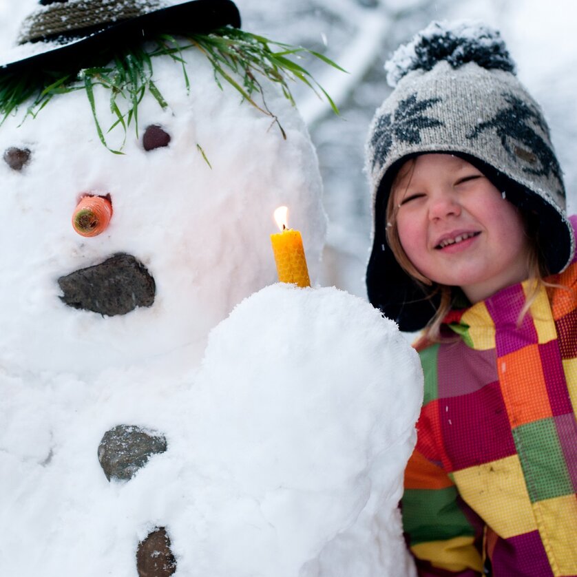 Advent in Graz I Büro für Weihnachtslieder | © Steirisches Volksliedwerk - Unterrainer Ein Junge und ein Schneemann mit einer Kerze und Noten. | © Steirisches Volksliedwerk - Unterrainer