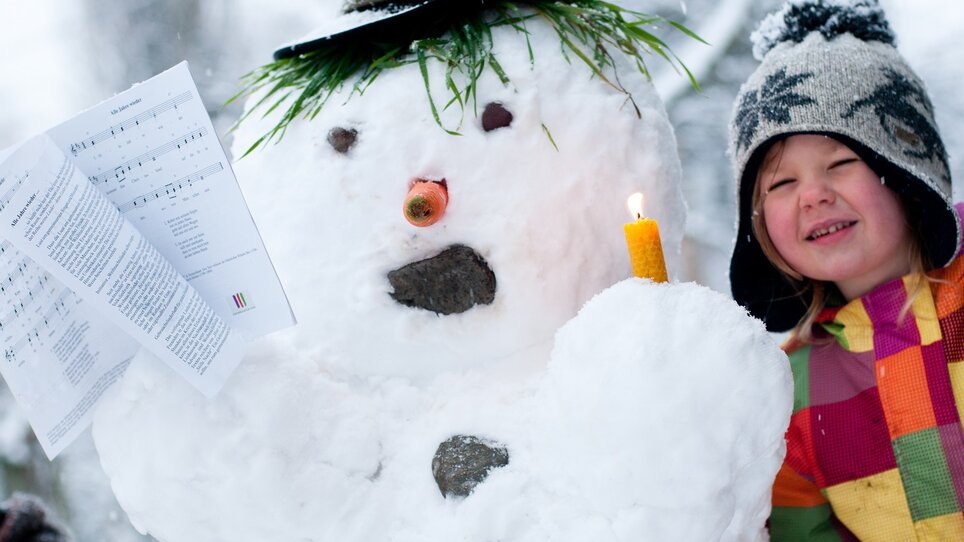 Ein Junge und ein Schneemann mit einer Kerze und Noten. | © Steirisches Volksliedwerk - Unterrainer