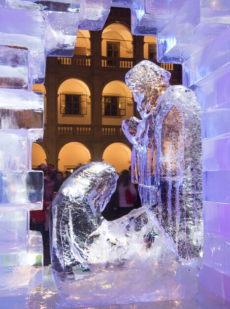An ice nativity scene displayed in a lit courtyard with people in the background. | © Graz Tourismus - Foto Fischer