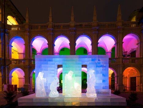Eiskunstwerk einer Krippe im Landhaushof, beleuchtet von bunten Lichtern. | © Graz Tourismus - Harry Schiffer