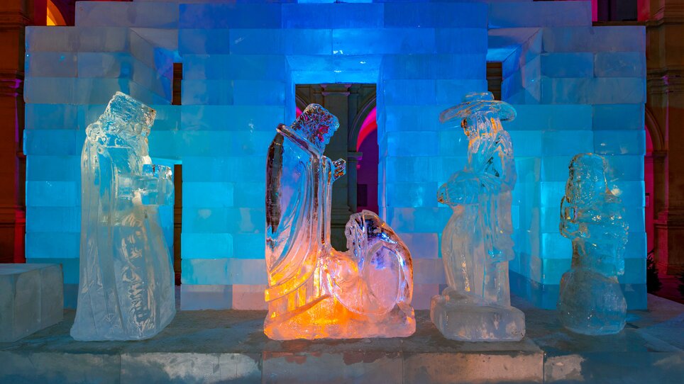Eiskunstwerk mit Figuren der Weihnachtskrippe, beleuchtet in bunten Farben. | © Graz Tourismus - Harry Schiffer