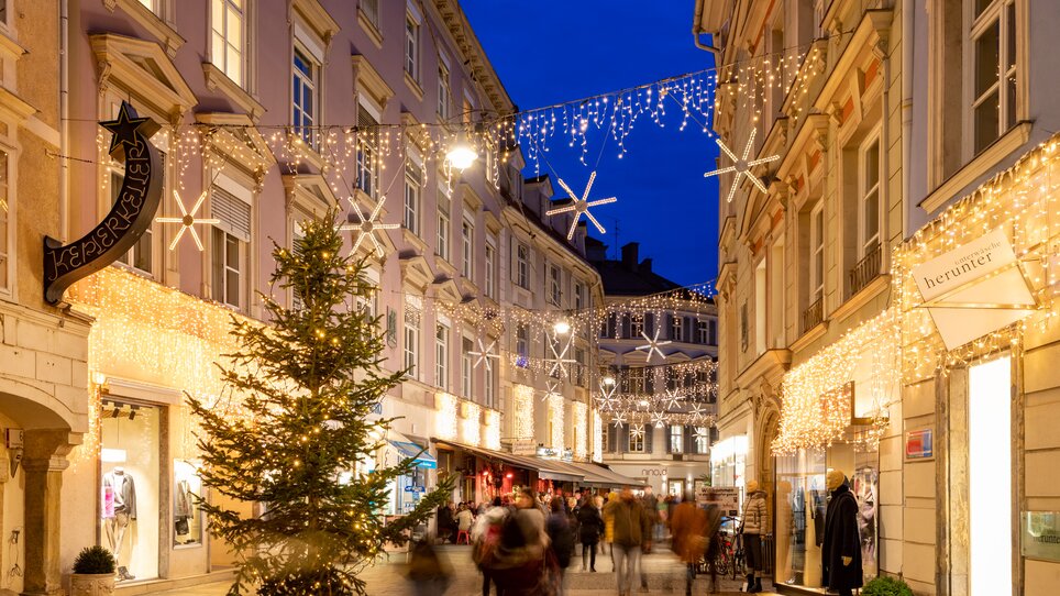Blick auf den festlich beleuchteten Krippenweg in der Stempfergasse mit Weihnachtsbaum und Lichterschmuck. | © Graz Tourismus-Harry Schiffer