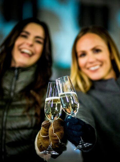 Zwei Frauen halten Sektgläser in der Nacht und lächeln. | © Graz Tourismus - Tom Lamm