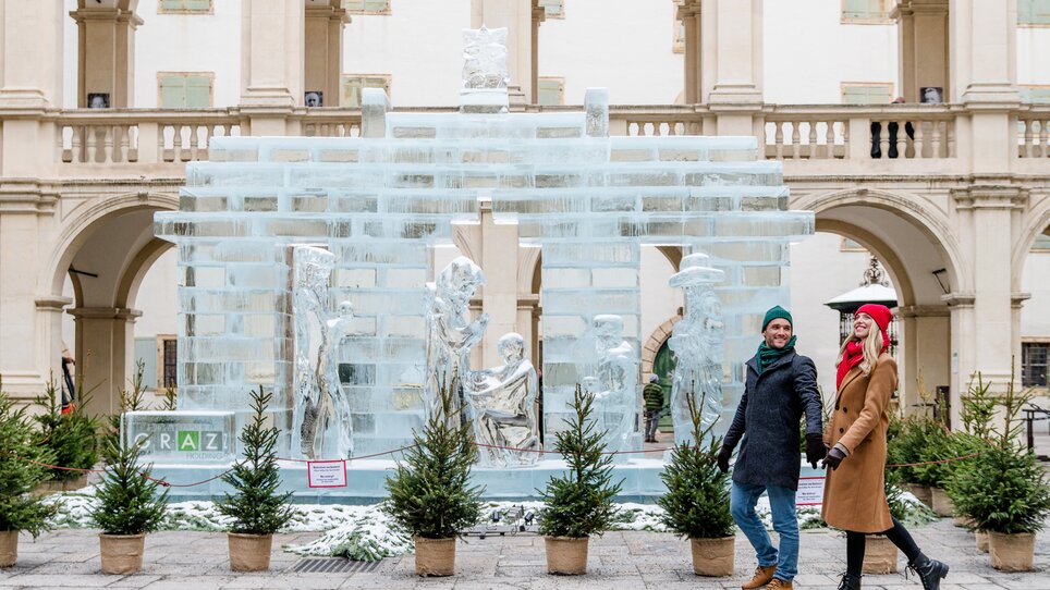 A couple walks in front of a stunning ice sculpture in Graz. | © Graz Tourismus - Mias Photoart