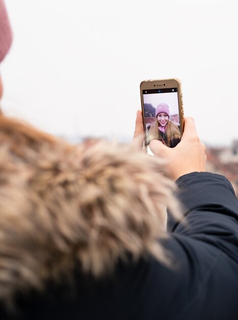 Una persona fa un selfie con Graz sullo sfondo in una giornata nuvolosa. | © Graz Tourismus - Katja Stadler