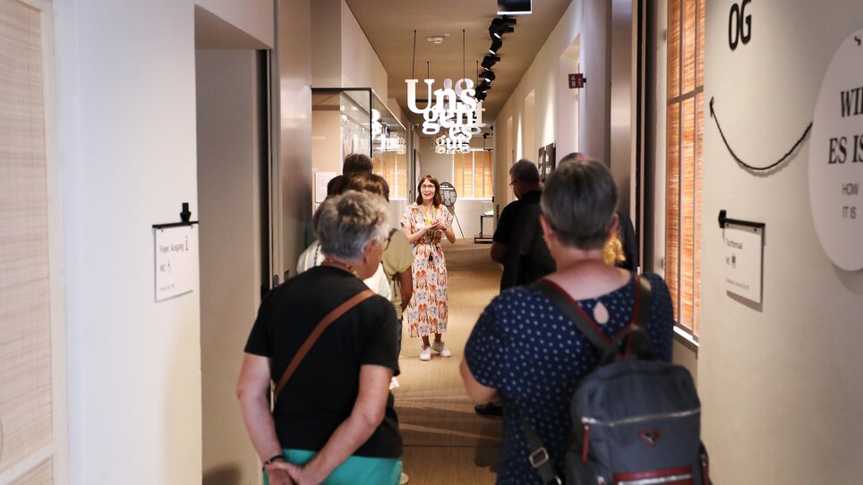Eine Gruppe von Besuchern hört gespannt einer Führerin im Museum zu. | © Volkskundemuseum Graz