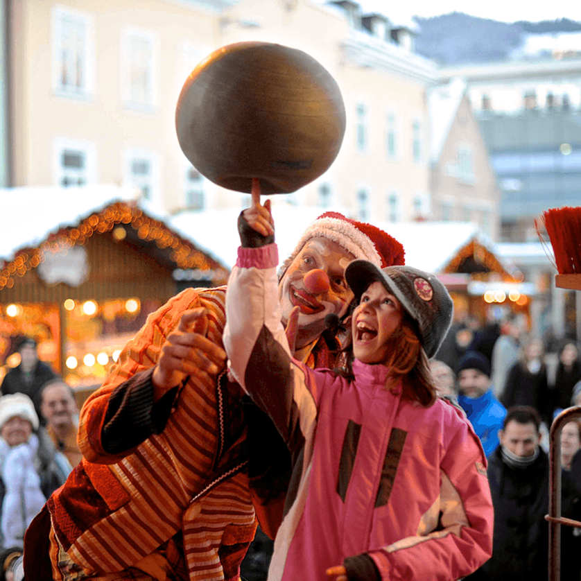 A clown and a girl together spin a plate at a Christmas market in Graz. | © Foto Jakotopia
