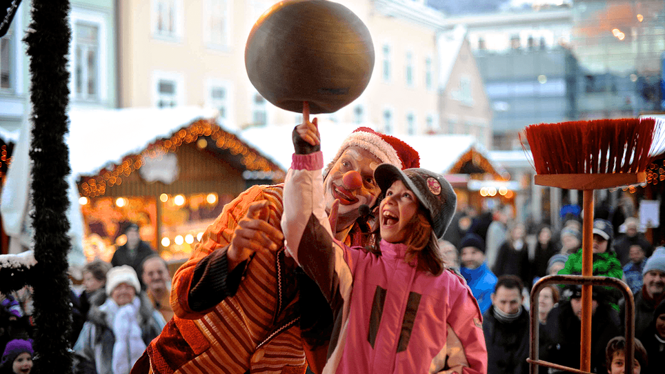 A clown and a girl together spin a plate at a Christmas market in Graz. | © Foto Jakotopia