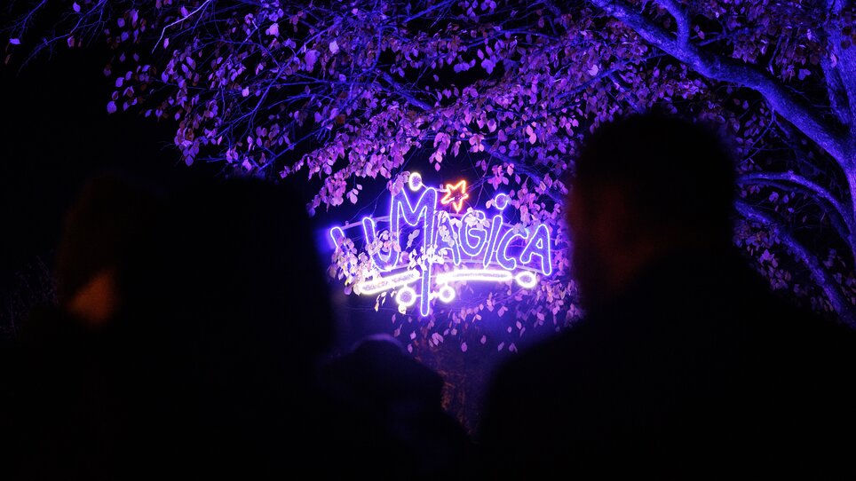 Luminosi colori e persone davanti a un insegna luminosa con 'LUMAGICA'. | © Erwin Scheriau