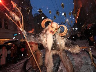 Il Krampus e le Perchten sfilano nella nevosa Graz, circondati da luci festive. | © Graz Tourismus - Harry Schiffer