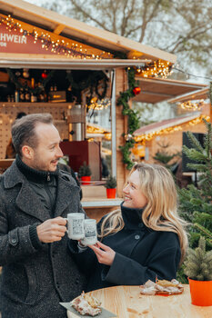 Paar in winterlicher Kleidung mit Glühwein am Adventmarkt. | © Mias Photoart