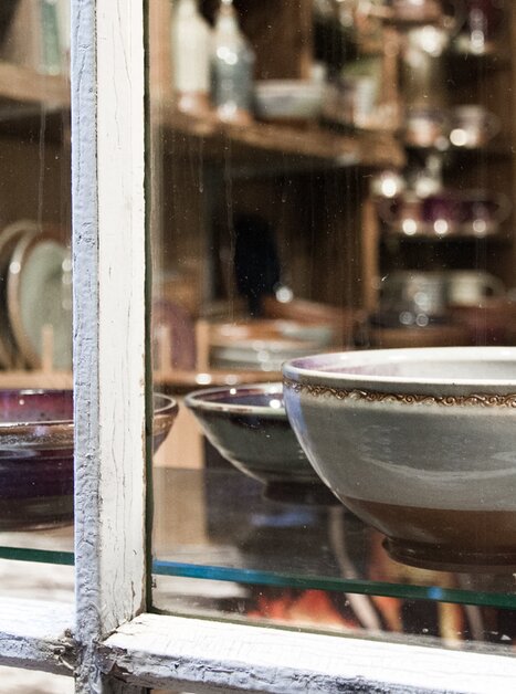 A variety of colorful pottery, including bowls and plates, on a shelf. | © Yola Moschitz