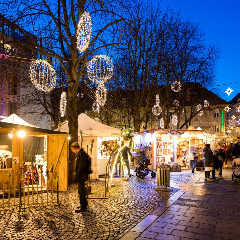 Advent in Graz I Handicraft market on Färberplatz square | © Graz Tourismus - Harry Schiffer Christmas market with stalls, lights, and visitors in Graz. | © Graz Tourismus - Harry Schiffer