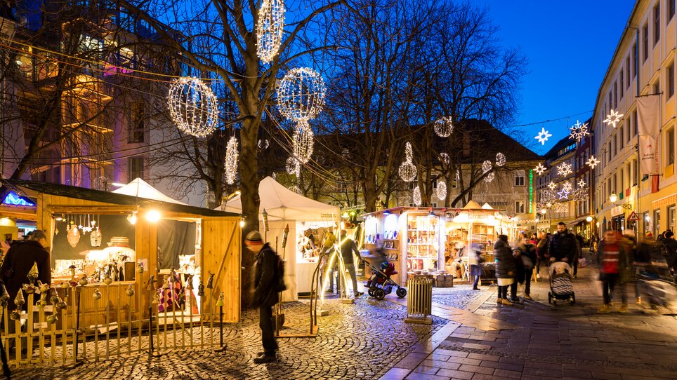 Weihnachtsmarkt mit Ständen, Lichtern und Besuchern in Graz. | © Graz Tourismus - Harry Schiffer