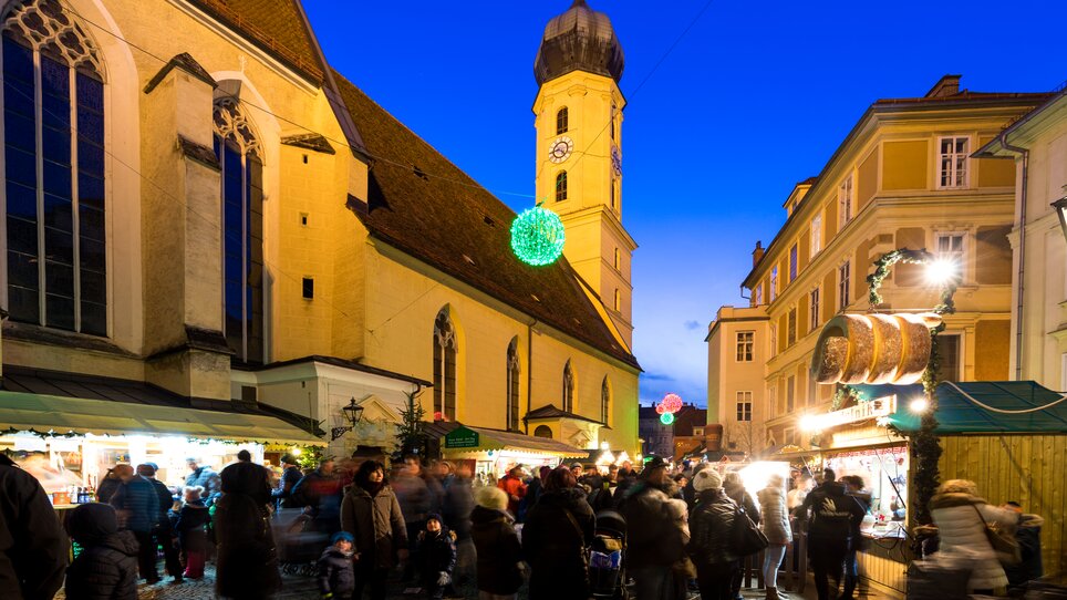 Belebte Szenerie des Christkindlmarktes im Franziskanerviertel bei Nacht mit festlich beleuchteten Ständen. | © Graz Tourismus - Harry Schiffer