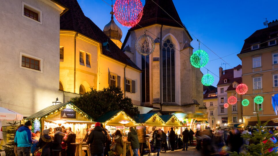 Weihnachtsmarkt im Franziskanerviertel, festlich beleuchtet mit Ständen und Menschen. | © Graz Tourismus - Harry Schiffer
