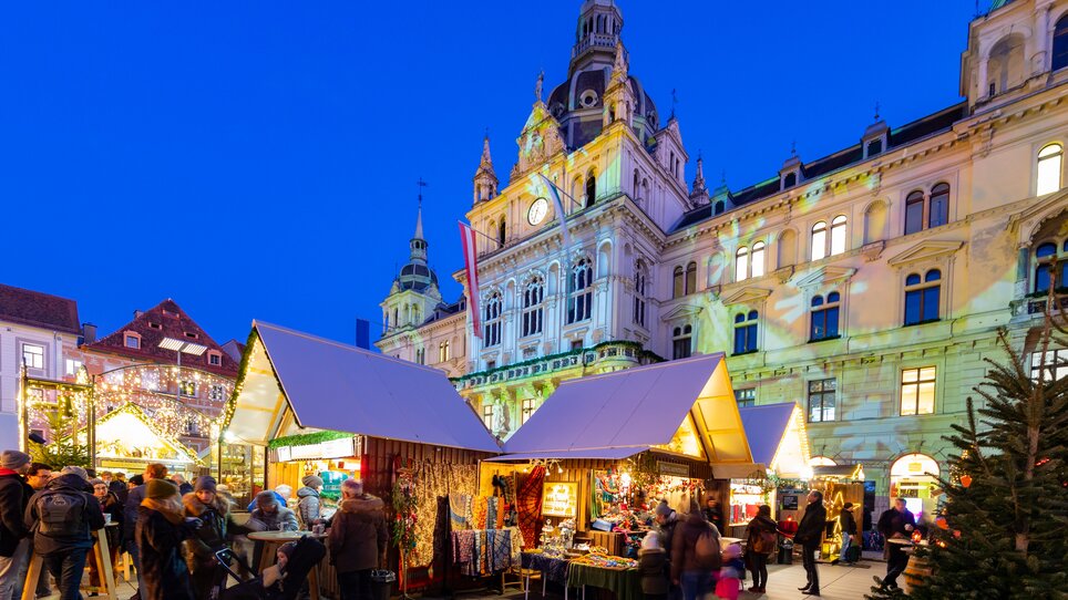 Christmas market in Graz with festively decorated stalls and Graz City Hall in the background. | © Graz Tourismus - Harry Schiffer