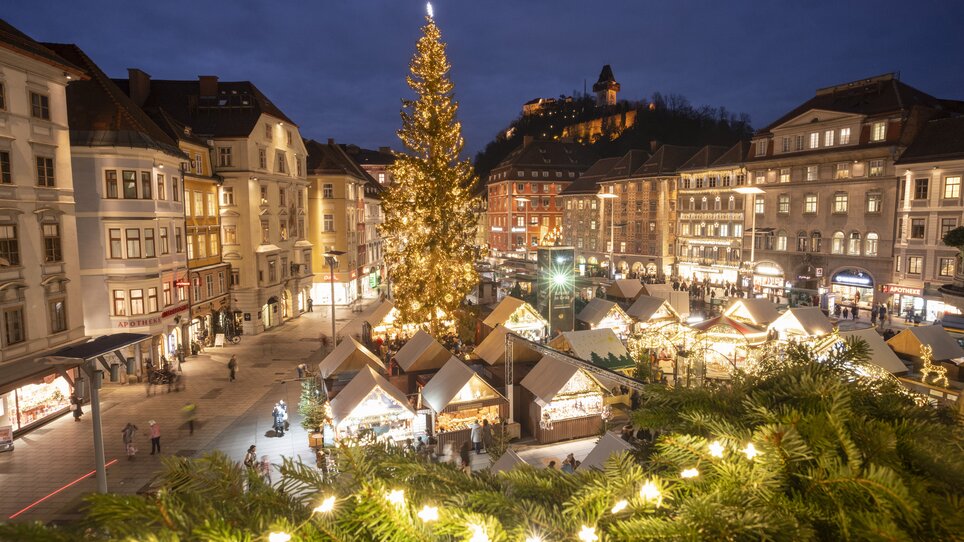 Weihnachtsmarkt am Hauptplatz in Graz mit beleuchtetem Weihnachtsbaum und Hütten. | © Vincent Croce