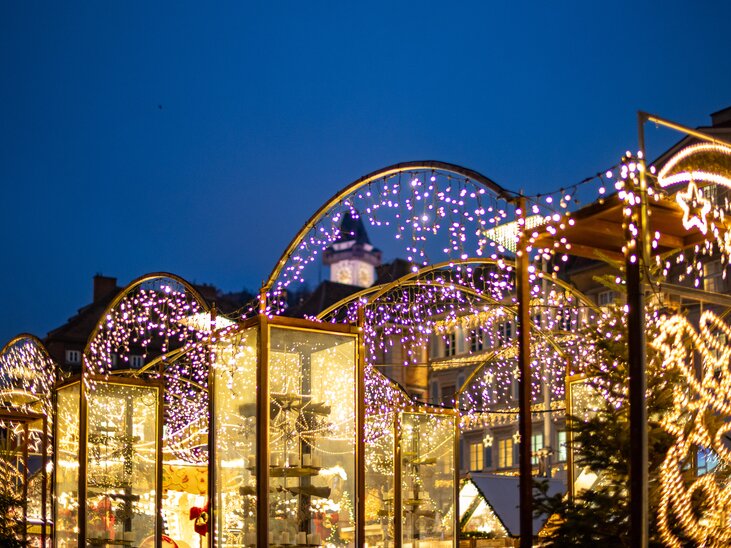 Illuminated Christmas market in Graz at night, with clock tower in the background. | © Graz Tourismus - Harry Schiffer