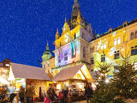 Christmas market with festive stalls and snow, Graz Town Hall in the background. | © Graz Tourismus - Harry Schiffer