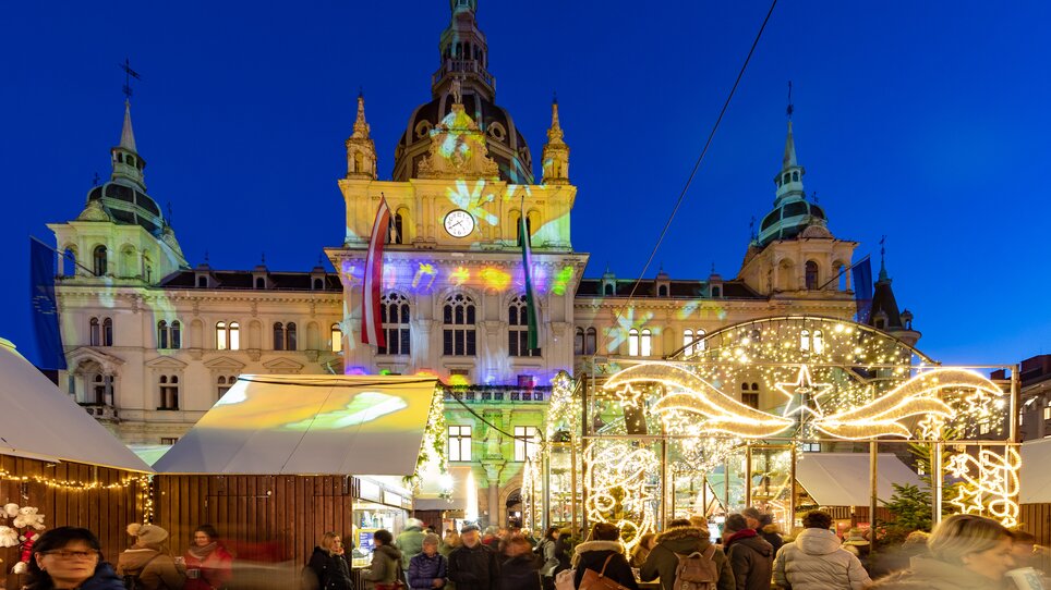 Beleuchteter Christkindlmarkt mit Menschen vor dem Grazer Rathaus zur Weihnachtszeit. | © Graz Tourismus - Harry Schiffer