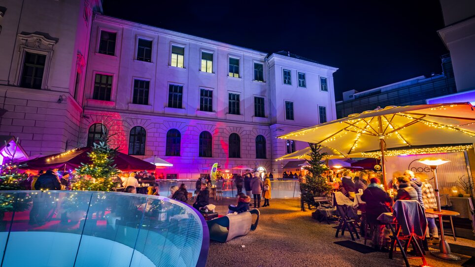 A festive atmosphere with lights and people at a Christmas market in the Joanneum quarter in Graz. | © Graz Tourismus - Werner Krug