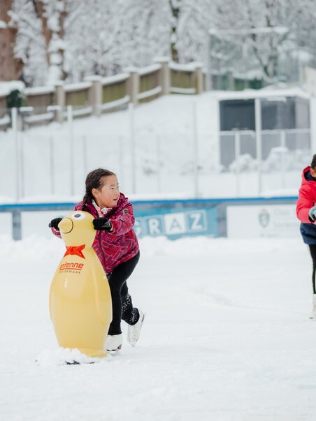 Kinder auf dem Eislaufplatz ziehen mit Pinguin-Hilfen über das Eis. | © Daniel Kindler