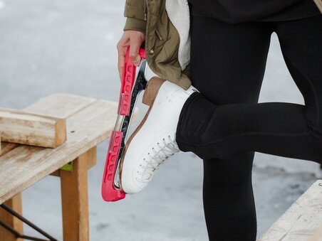 Eine Person bindet sich die Schlittschuhe an einem Eislaufplatz. | © Daniel Kindler