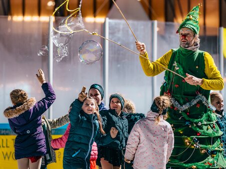 Kinder beim Eislaufen, umgeben von einem Weihnachtsmann im Kostüm. | © Kuro Simon