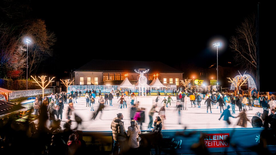 Nachtaufnahme eines Eislaufplatzes mit vielen Menschen in Graz. | © Kuro Simon