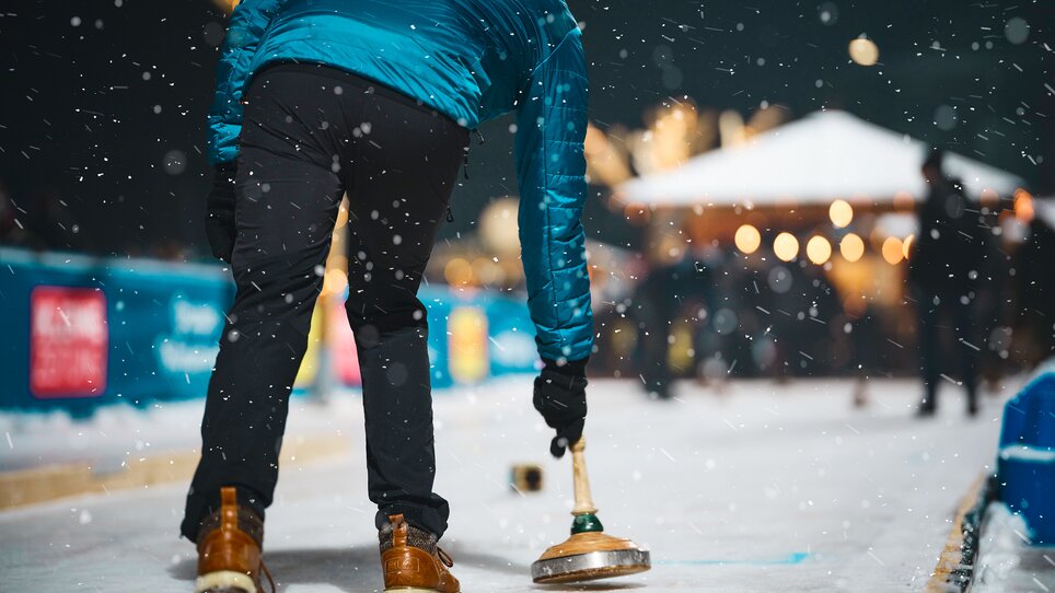Ein Curling-Spieler auf einem festlich dekorierten Eislaufplatz. | © Stefan Leitner