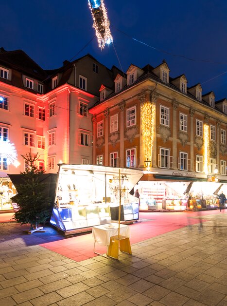 Illuminated buildings and stalls at the Christmas market in Graz, festive decorations. | © Graz Tourismus - Harry Schiffer