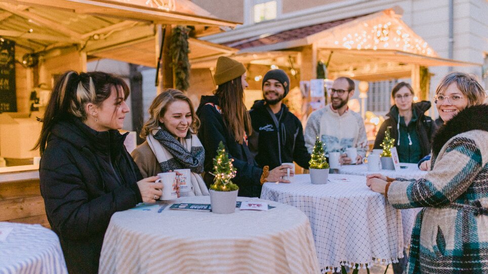 Menschen stehen an Tischen und genießen Getränke in festlicher Atmosphäre. | © Evgenia Rieger Photography
