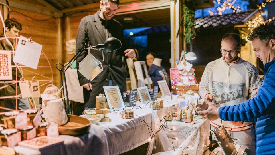 Weihnachtsmarkt mit Ständen und Besuchern, festlich beleuchtet. | © Evgenia Rieger Photography