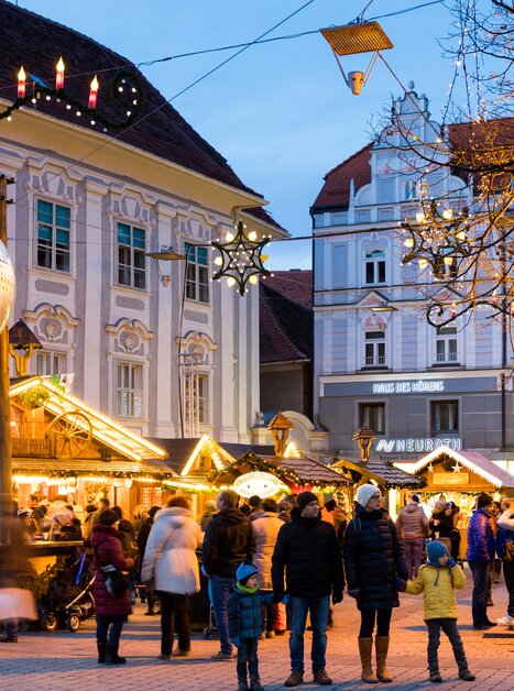 Blick auf den Christkindlmarkt am Südtiroler Platz in Graz, mit festlicher Beleuchtung und vielen Besuchern. | © Graz Tourismus - Harry Schiffer