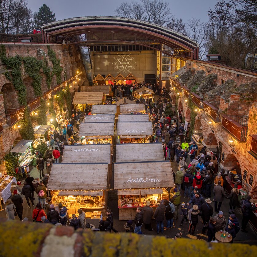 Advent in Graz I "Aufsteirern"- Weihnachtsmarkt am Schlossberg | © ivents Der Weihnachtsmarkt auf dem Schlossberg in Graz, mit stimmungsvoller Beleuchtung und vielen Besuchern, die die Stände erkunden. | © ivents