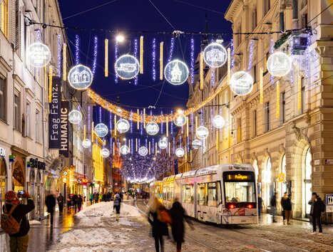 Beleuchtete Herrengasse in Graz mit Tram und Weihnachtsdekoration. | © Graz Tourismus - Harry Schiffer