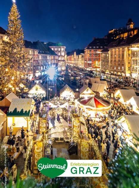 Christmas market in Graz with a view of the Graz Clock Tower and the festively illuminated city.