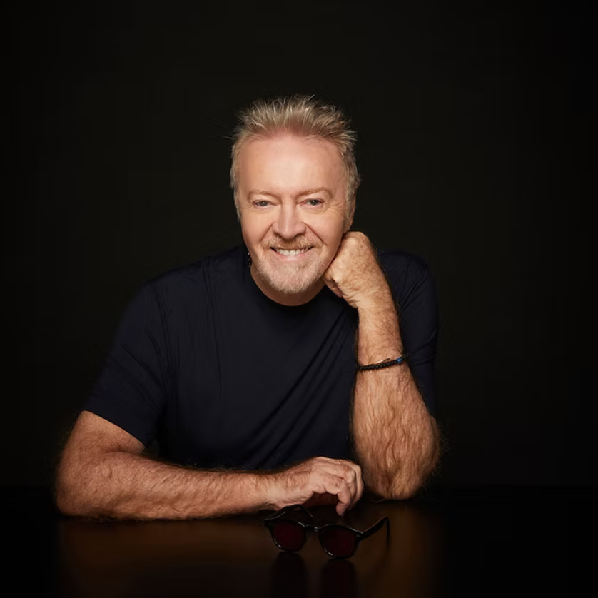 il cantattore Umberto Tozzi siedi a una tavola indossando un T-Shirt nero | © Umberto Tozzi