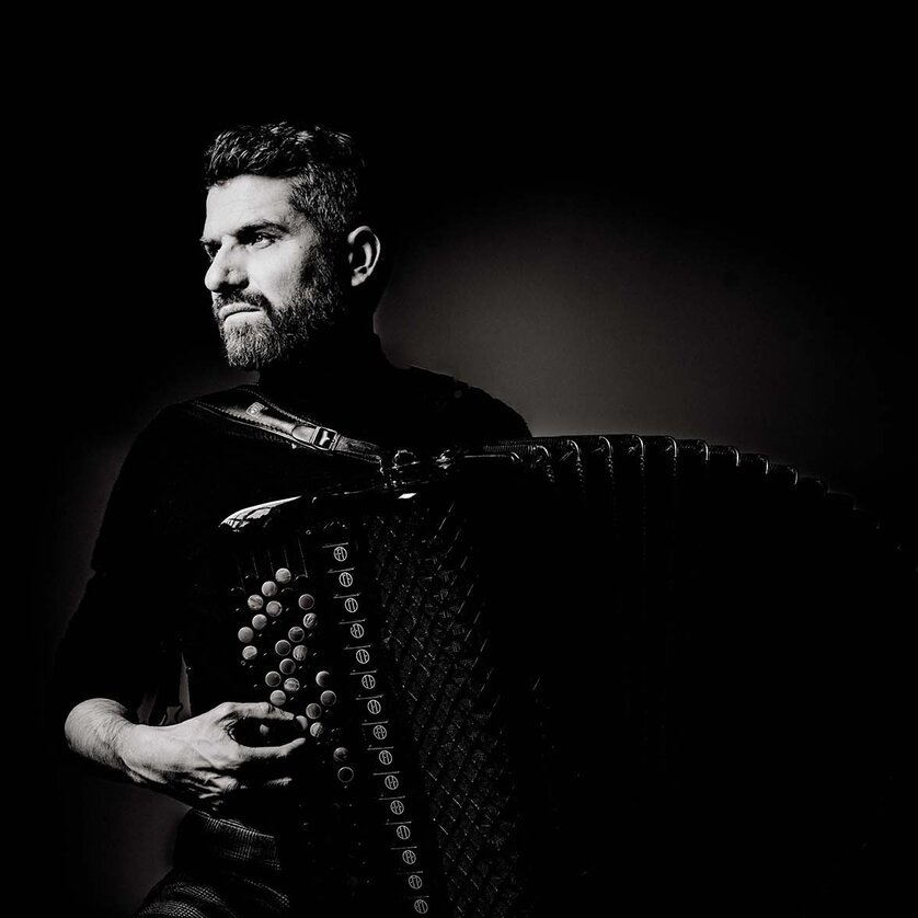 Christian Bakanic plays the accordion in dramatic lighting. | © Andre Grilc