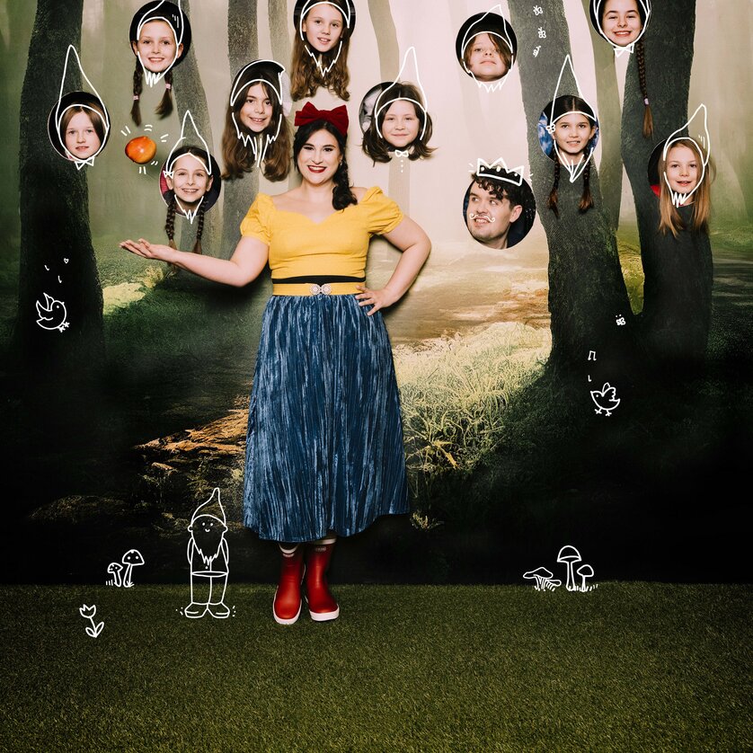 Frau als Schneewittchen mit Kindern als Zwerge vor Waldkulisse mit gezeichneten Elementen | © Oper Graz - Ingo Pertramer
