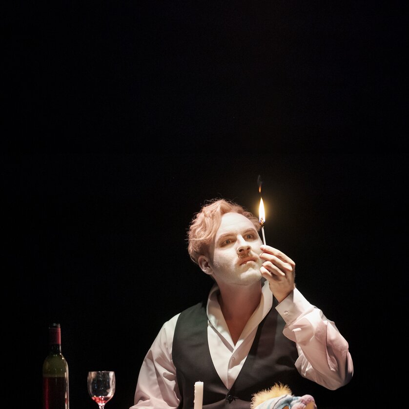 Ein Schauspieler mit weißem Gesicht, hält eine brennende Kerze während einer Darbietung. | © Oper Graz - Werner-Kmetitsch
