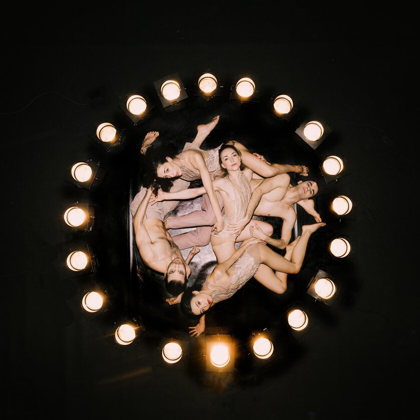 Ring Ballett Graz | © Oper Graz - Ingo Pertramer Five dancers lie in a circle under stage lights on a dark background | © Oper Graz - Ingo Pertramer