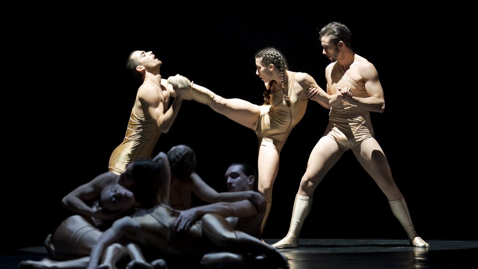 Dancers in golden outfits showcase powerful movements on stage. | © Werner Kmetitsch - Oper Graz